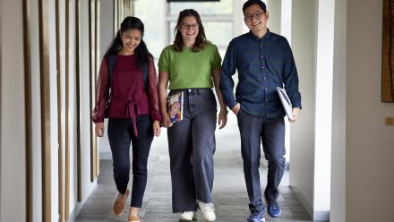 Three ANU students walking down a hallway