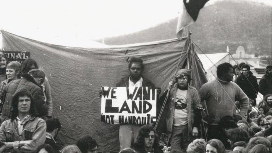 Alan Sharpley with a placard at the Aboriginal Tent Embassy, c.1972. (NLA)