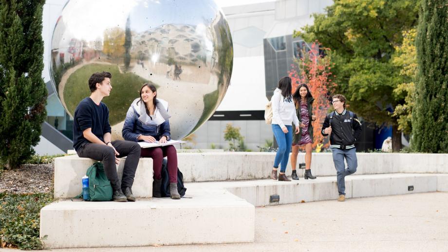 Image of students talking in small groups on campus.